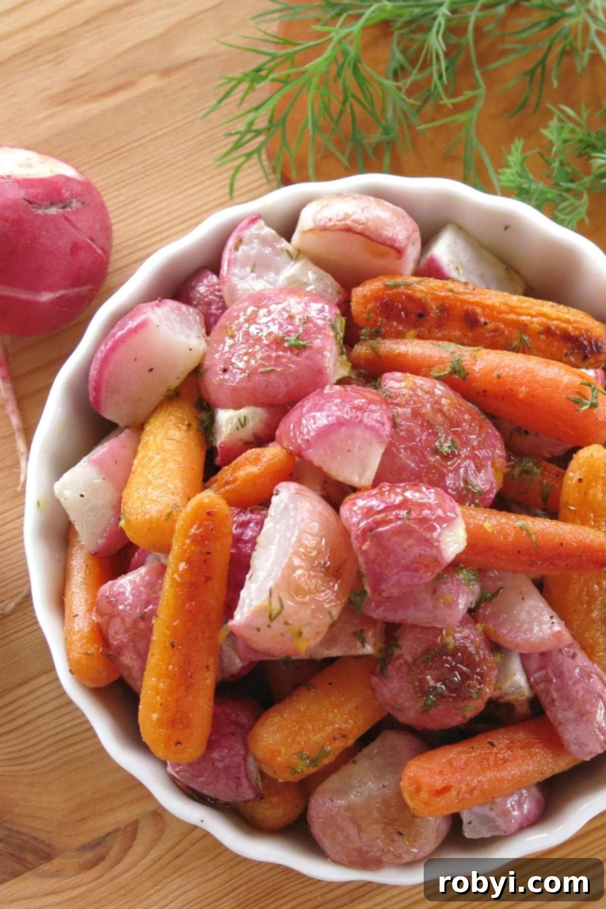 A beautifully presented serving dish filled with perfectly oven-roasted radishes and carrots, garnished with fresh dill sprigs in the background, highlighting the vibrant colors and appealing texture of the dish.