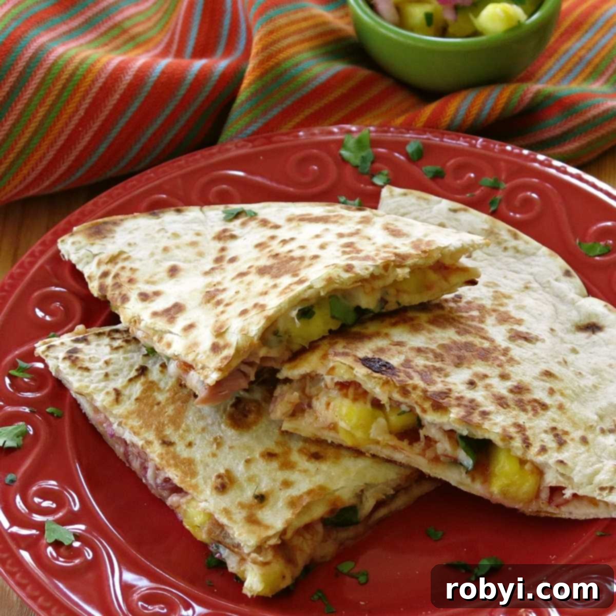 Hawaiian quesadilla with ham, pineapple, and cheese cut into triangles on a plate, ready to serve.