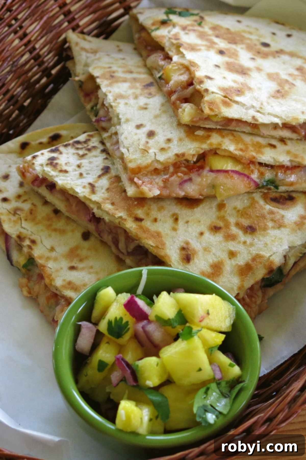 A rustic basket filled with freshly made Hawaiian ham quesadillas, accompanied by a vibrant pineapple salsa.