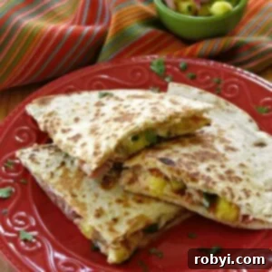Close-up of a Hawaiian Quesadilla with ham, pineapple, and cheese cut into triangles on a plate.