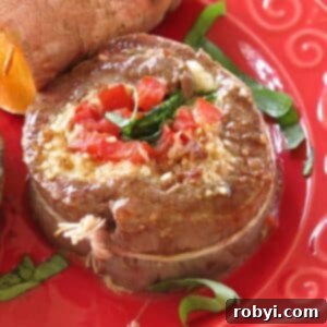 Flank steak pinwheel stuffed with spinach, tomatoes, and mozzarella cheese on a red plate.