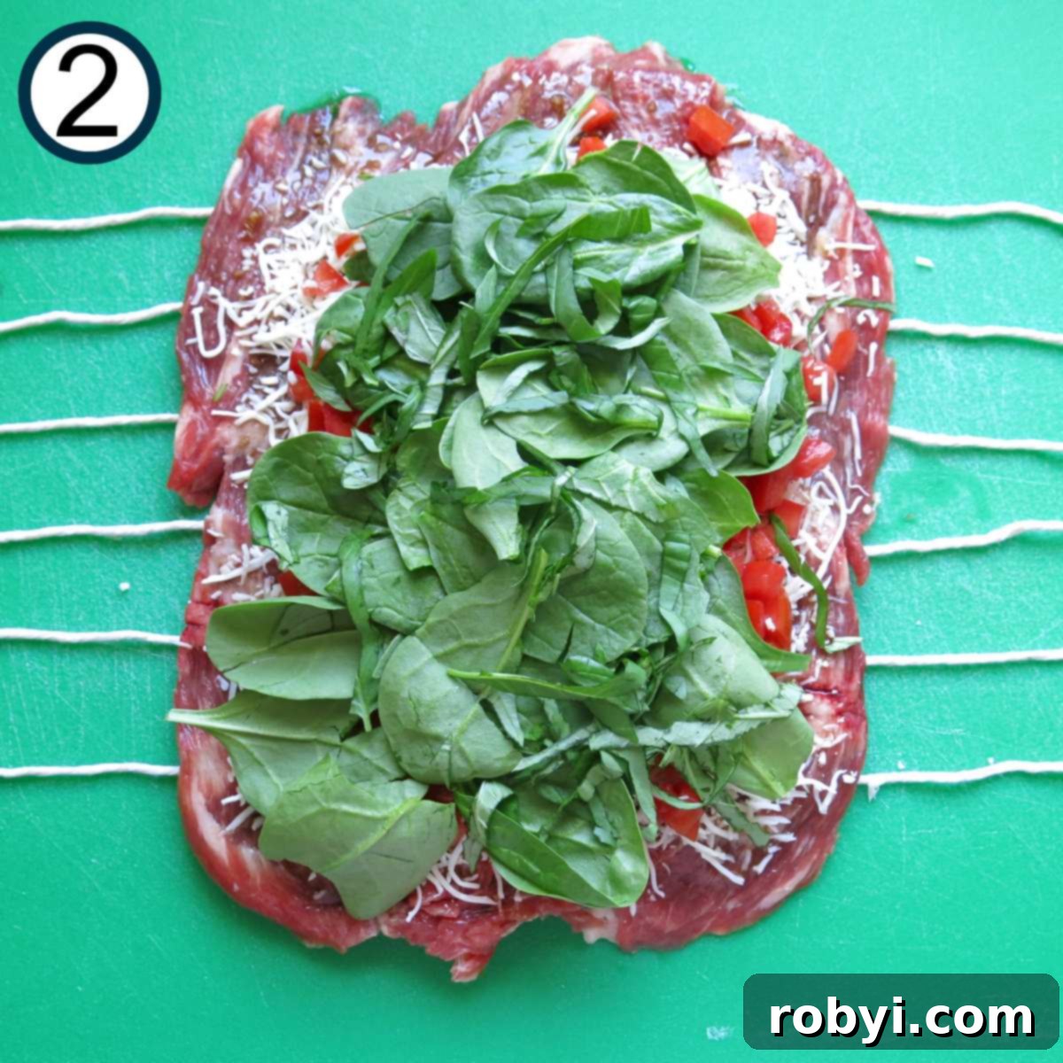 Shredded mozzarella cheese, diced tomatoes, and spinach leaves on top of a butterflied flank steak.