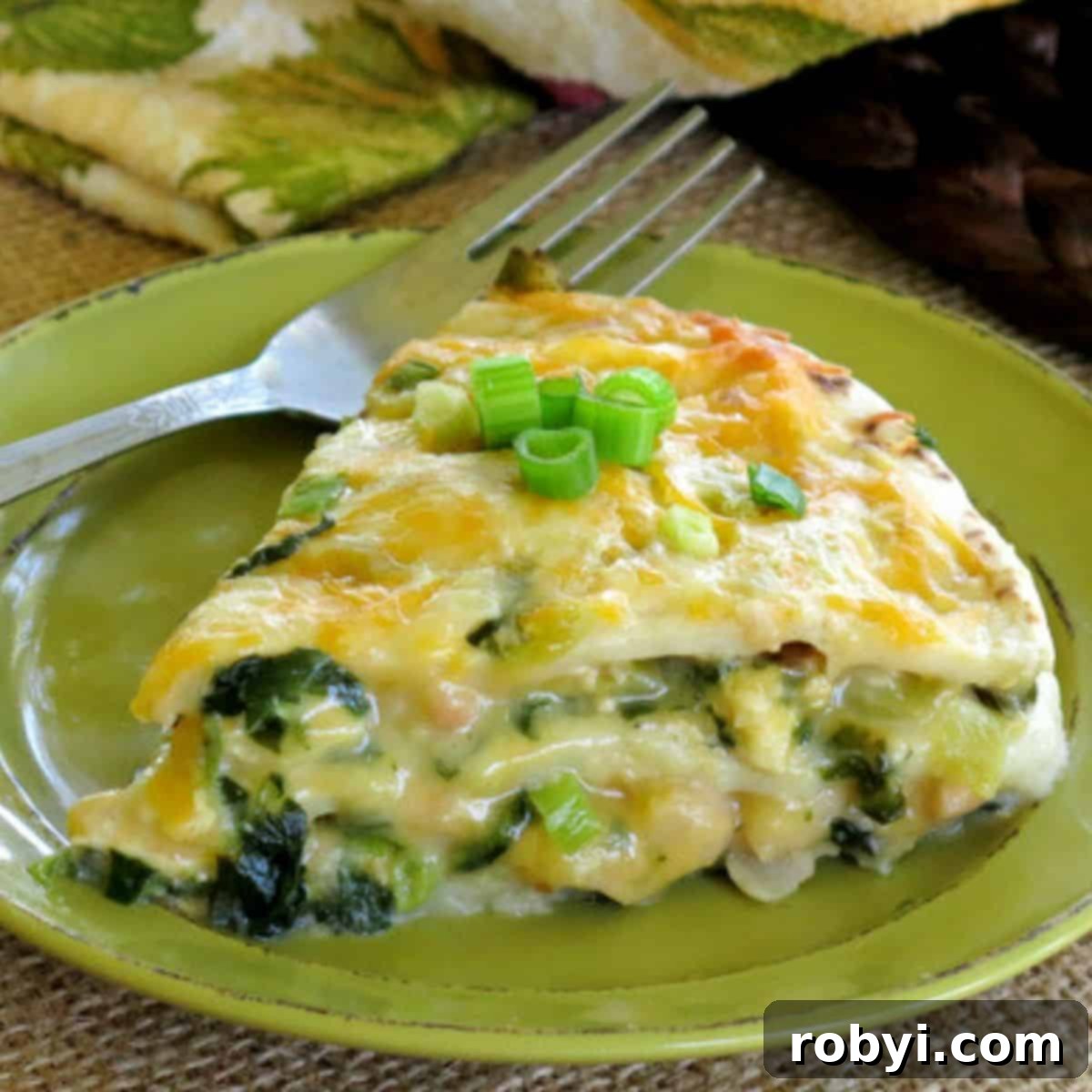 Repurpose Your Chicken Effortless Enchilada Bake 2 A perfectly baked slice of Creamy White Chicken Enchilada Pie Casserole on a plate with a fork, showing its distinct layers.