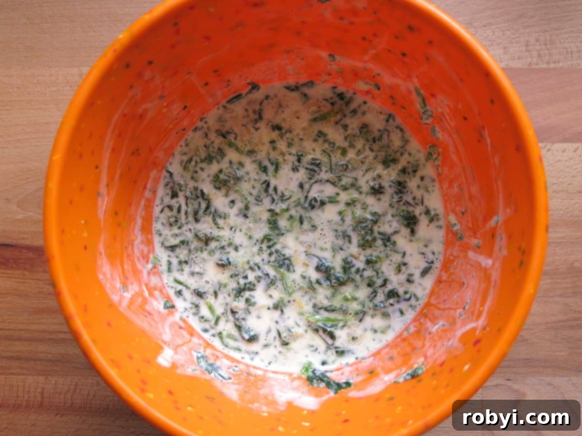 Repurpose Your Chicken Effortless Enchilada Bake 3 A bowl of creamy white enchilada sauce, subtly showing flecks of green spinach mixed within.