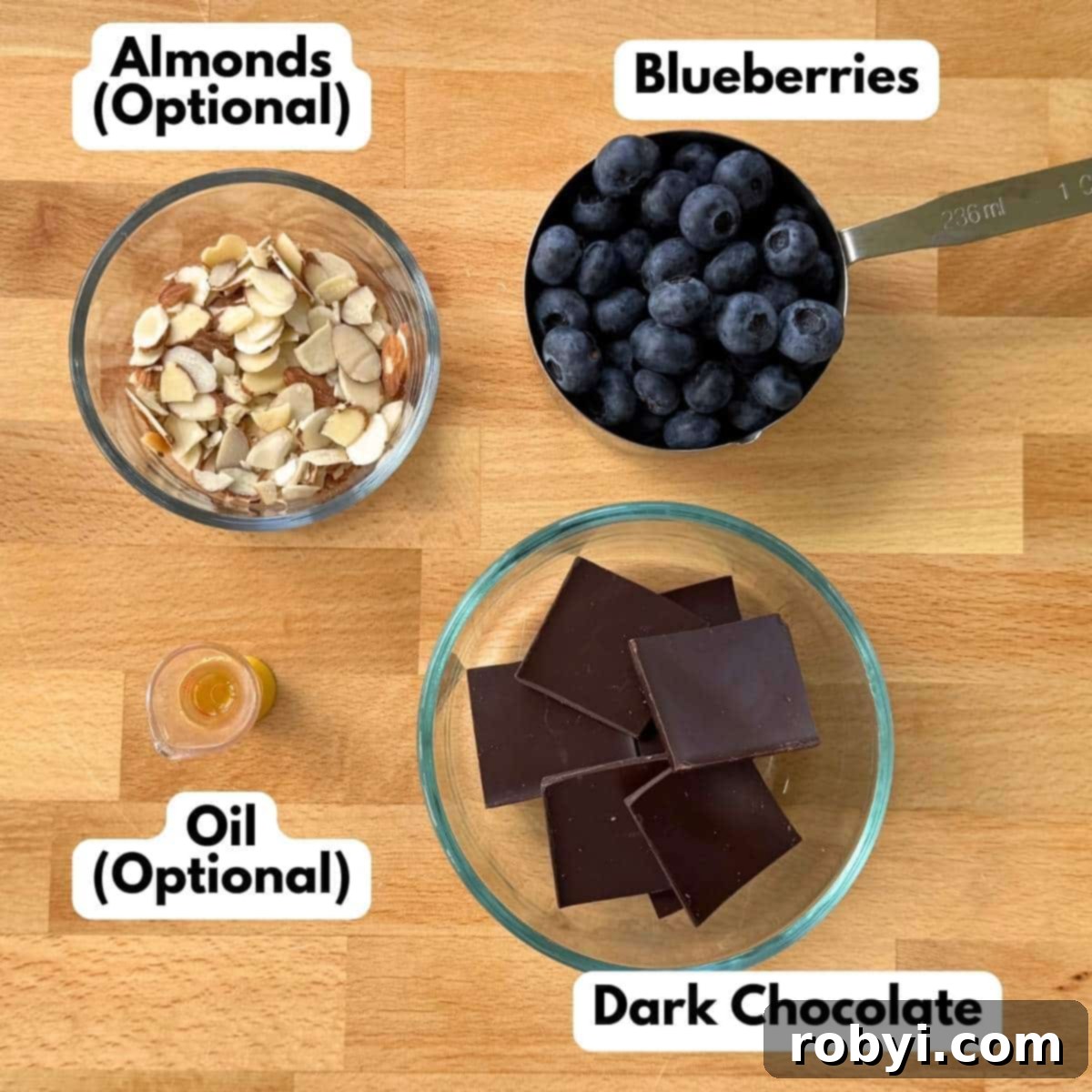 Chocolate square, blueberries, oil, and sliced almonds on a butcher block cutting board.