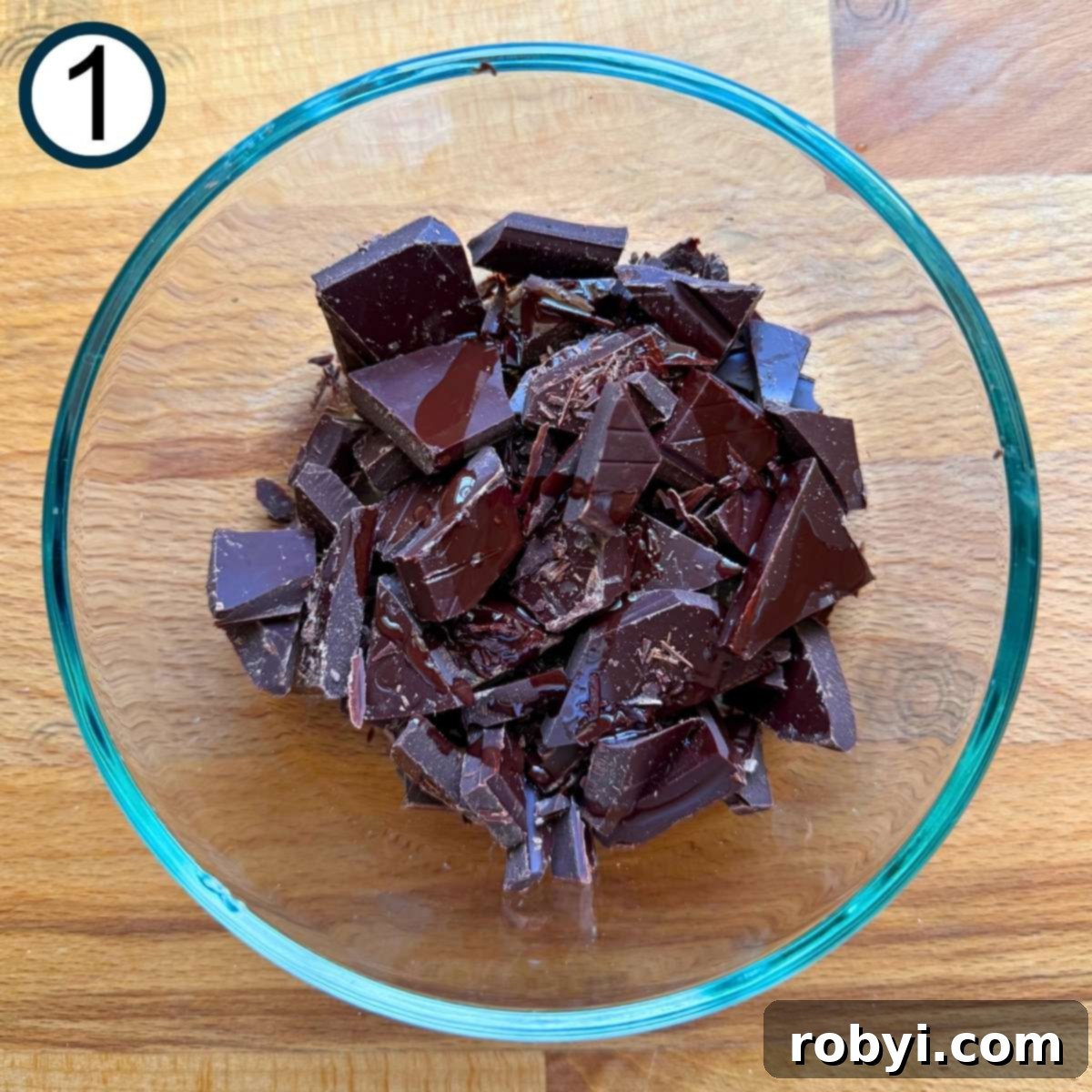Chopped chocolate and oil in a glass bowl.