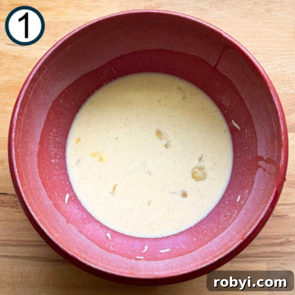 A red bowl containing whisked eggs, milk, salt, and white pepper, forming the base of the quiche mixture before other ingredients are added.