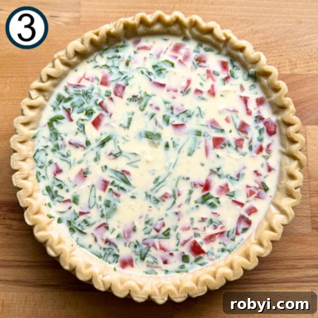 The vibrant tomato bacon quiche filling poured into a pie crust, nestled perfectly and ready for the oven.