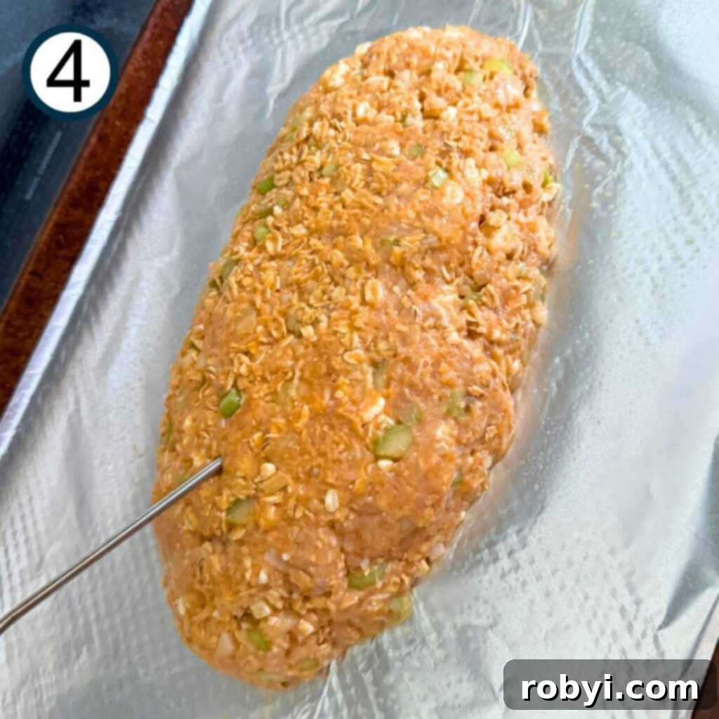Buffalo chicken mixture formed into a meatloaf shape on a pan with a thermometer.
