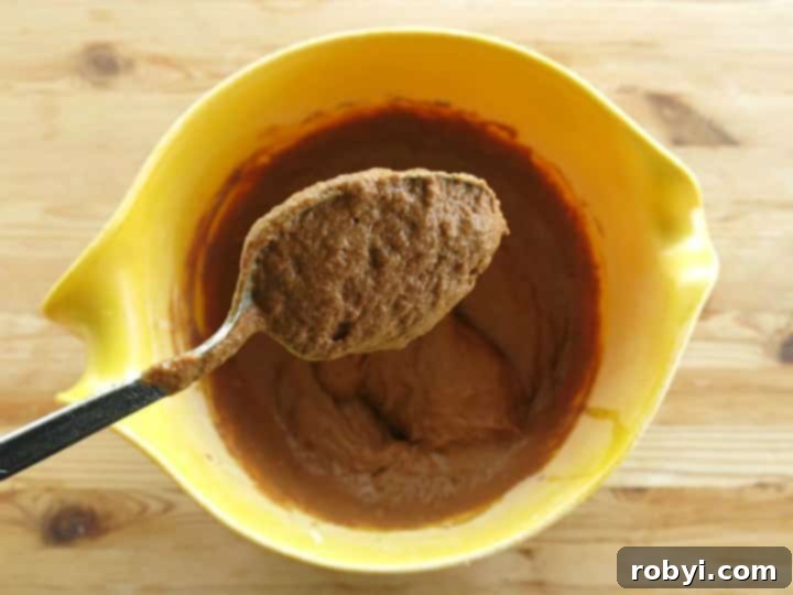 Healthy Chocolate Pumpkin Muffin batter on a spoon over a mixing bowl.