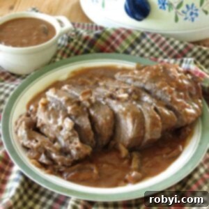 Beef shoulder roast topped with red wine mushroom sauce on a plate.