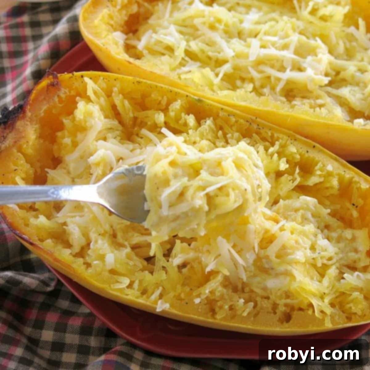 Fork lifting spaghetti squash alfredo strands out of the gourd.