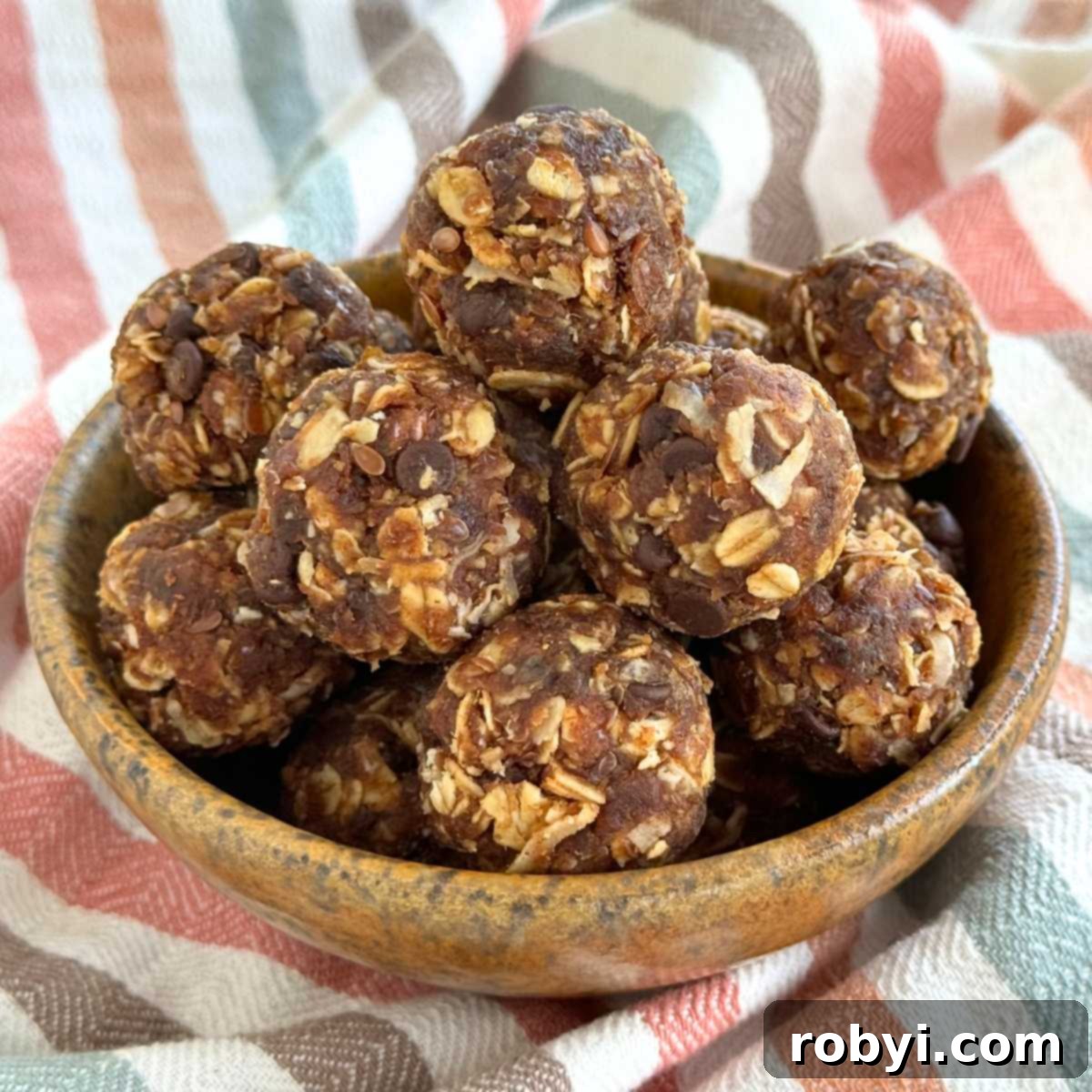 Healthy energy balls made with Medjool dates and oatmeal piled in a brown bowl on a colorful napkin.