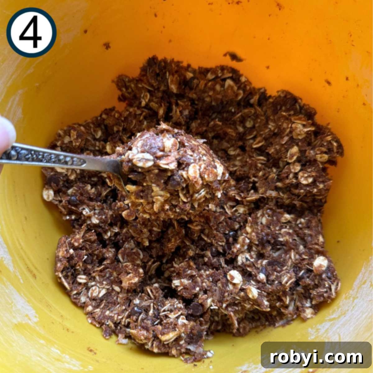 Sunflower seed butter, pureed dates, and vanilla extract mixed with dry ingredients in a yellow bowl.