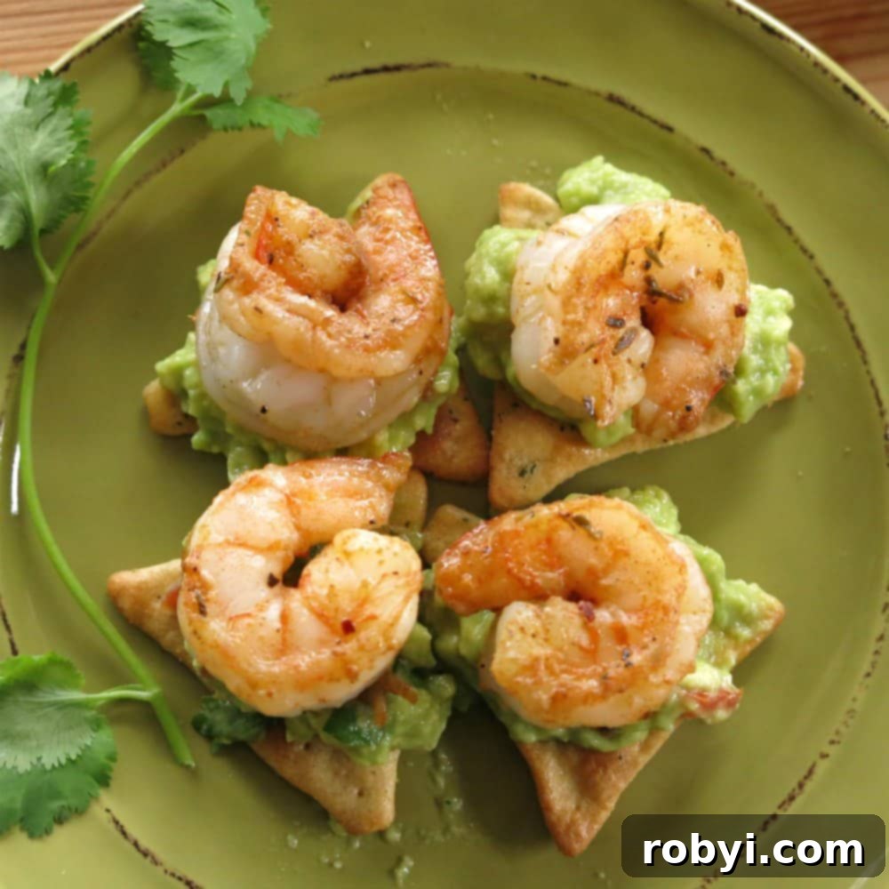 Fiery Cajun Shrimp Guac Scoops 5 Four elegantly presented Cajun Shrimp Guacamole Bites on cucumber rounds, garnished with fresh cilantro, on a small serving plate.
