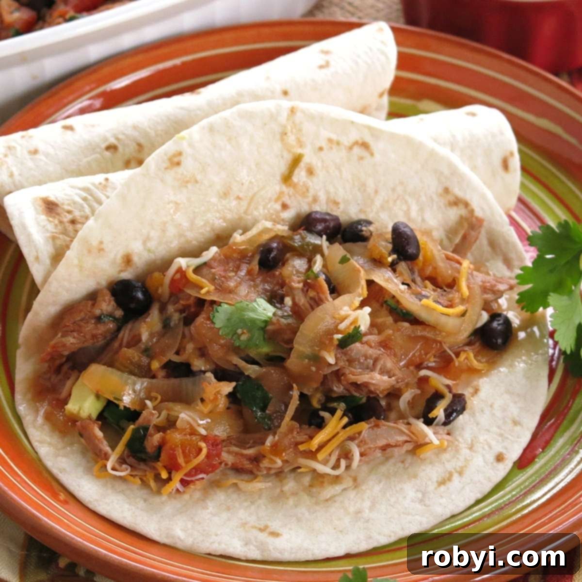 Delicious pork tacos filled generously with black beans and melted cheese in a soft flour tortilla, garnished with fresh cilantro.