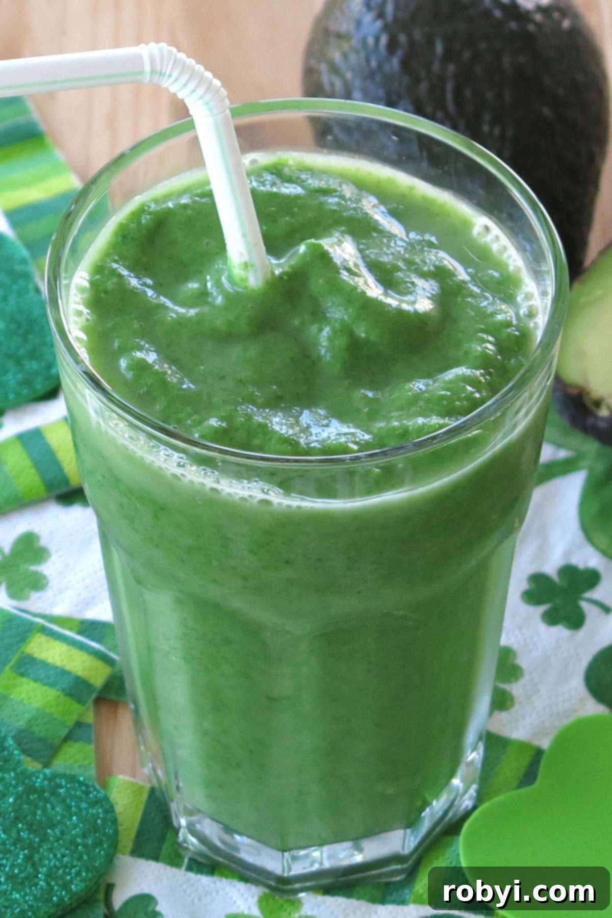 Creamy Green Tropical Elixir 4 Pineapple green smoothie with avocado in a glass with a straw.