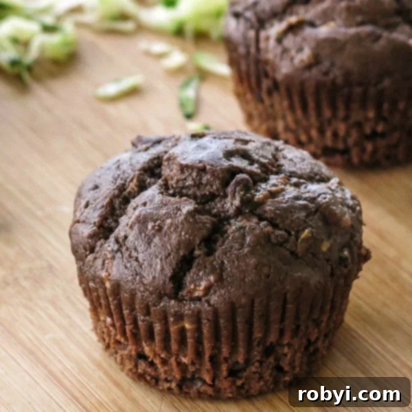 A single Death by Chocolate Zucchini Muffin, perfectly baked and inviting, placed on a rustic cutting board.