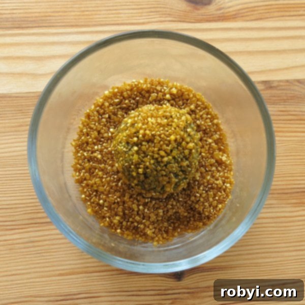 Oreo balls dipped in bowl of gold sprinkles.