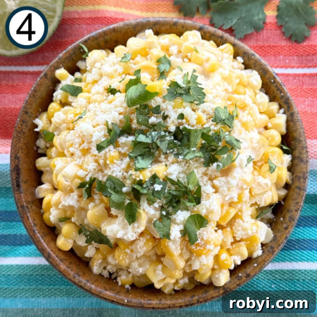 Creamy Elote Cups 7 Mexican street corn in a brown serving bowl topped with Cotija cheese and chopped cilantro.