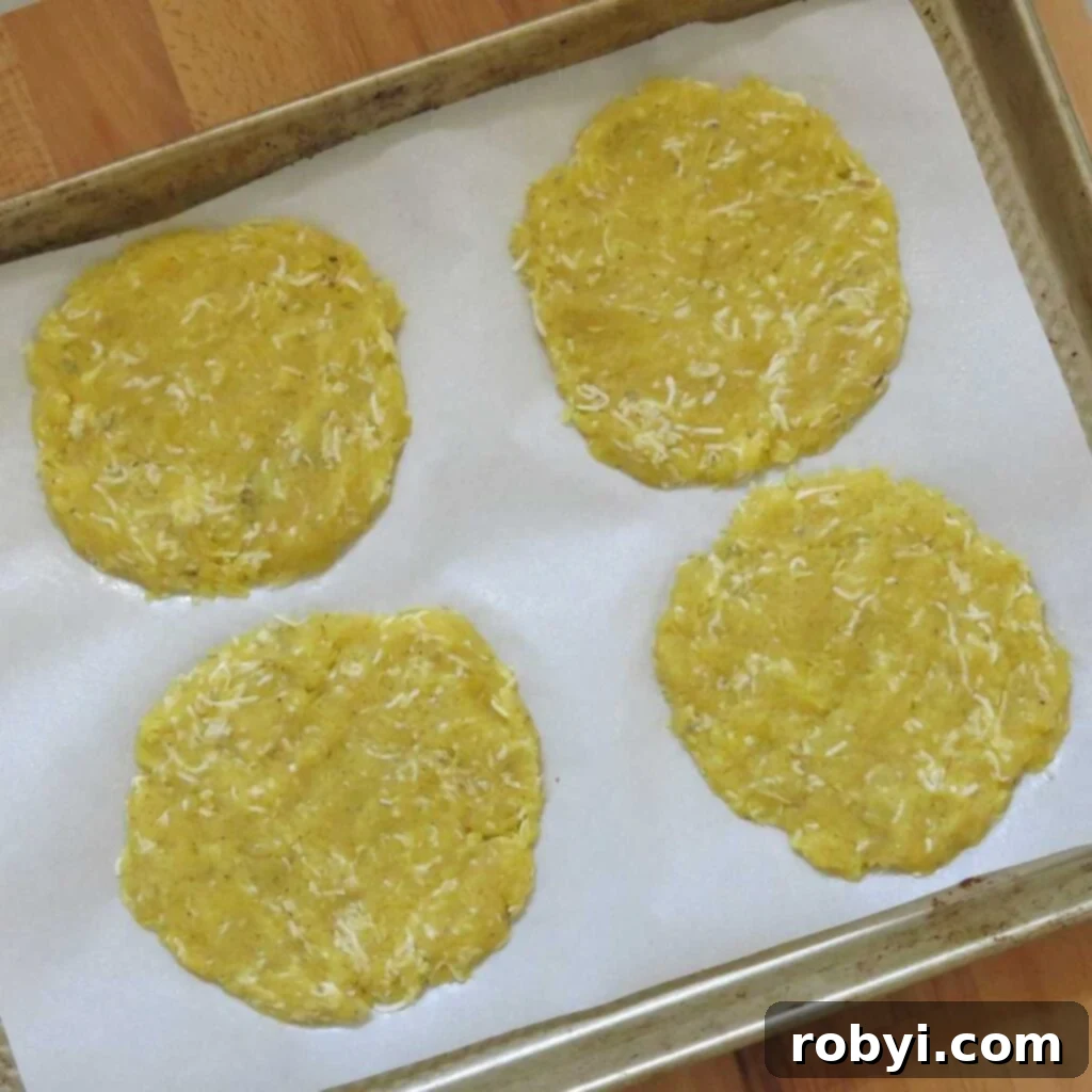Four perfectly shaped, uncooked spaghetti squash pizza crusts arranged on a baking sheet lined with parchment paper, awaiting their transformation in the oven.