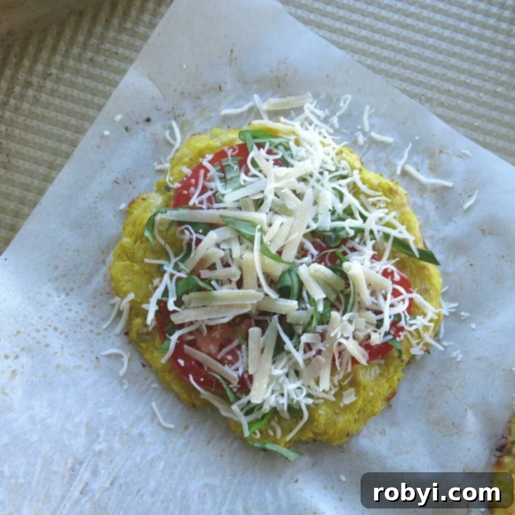 A partially cooked spaghetti squash pizza crust generously spread with vibrant pizza sauce, adorned with fresh tomato slices, fragrant basil leaves, and a sprinkle of mozzarella cheese, poised for its final bake.