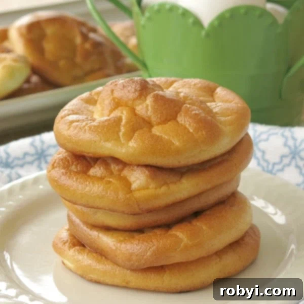 Stacks of fluffy, golden-brown cloud bread rounds on a clean white plate, ready to be enjoyed.