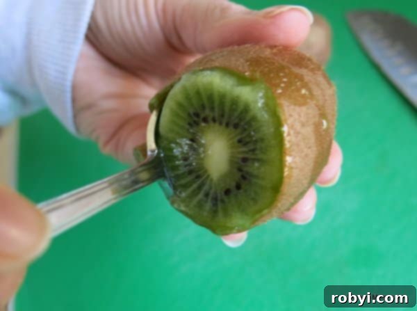 spoon inside skin of kiwi demonstrating trick for taking skin off