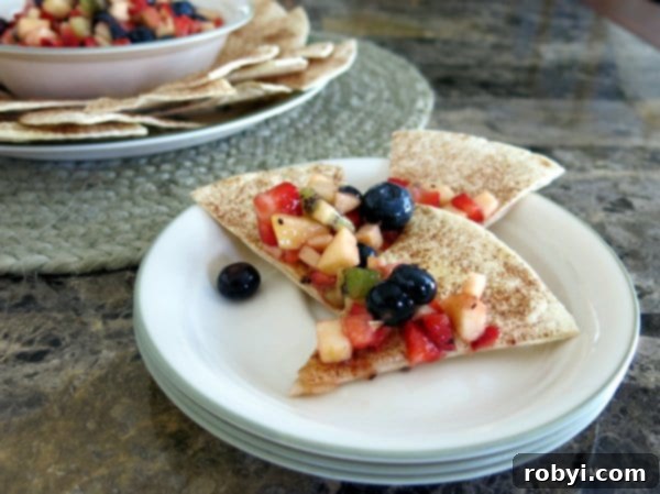 Fruit Salsa on top of cinnamon chips on a stack of plates.