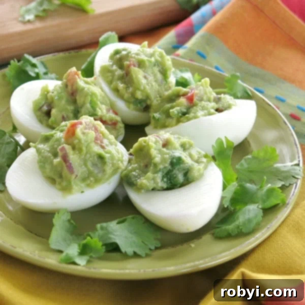 Five beautifully stuffed egg halves with creamy green guacamole, garnished with fresh herbs and ready to serve.