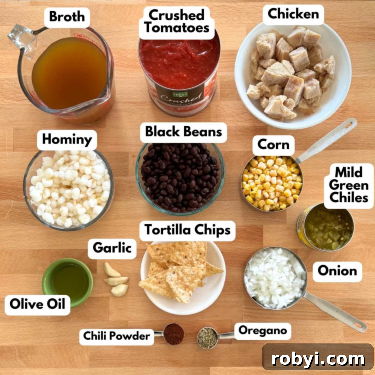 Labeled ingredients to make chicken tortilla soup: chicken, black beans, corn, hominy, crushed tomatoes, diced onion, broth, tortilla chips, mild green chiles, olive oil, garlic, chili powder, and oregano.