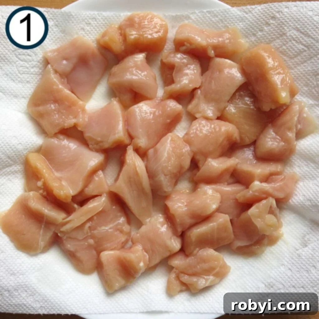 Raw, uniformly cut chicken pieces laid out on a paper towel-lined plate, ready for preparation.