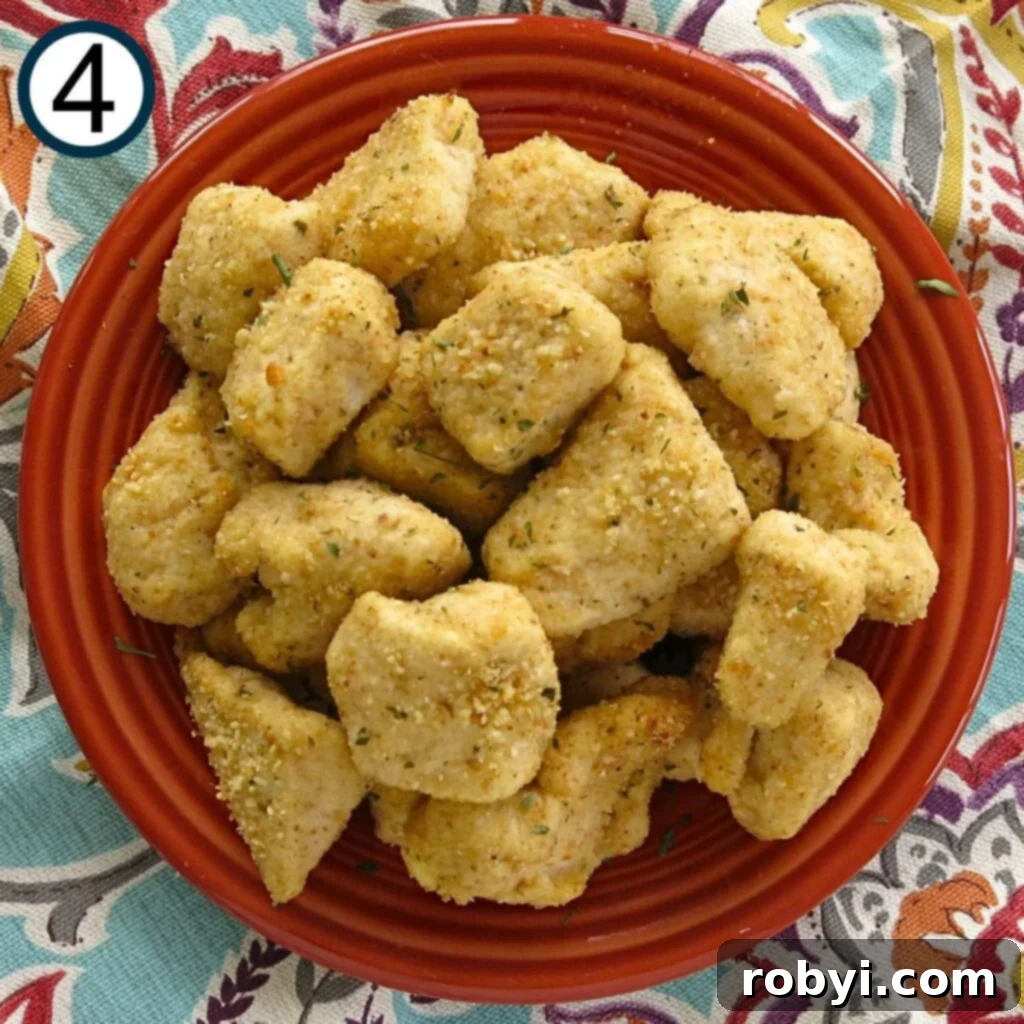 Perfectly cooked, golden-brown garlic Parmesan chicken nuggets presented on a dark orange plate, garnished lightly.