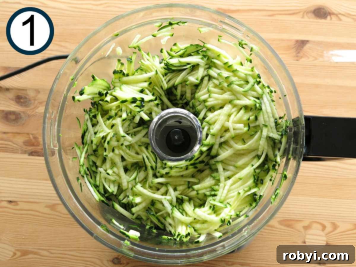 Grated zucchini in the base of a food processor.