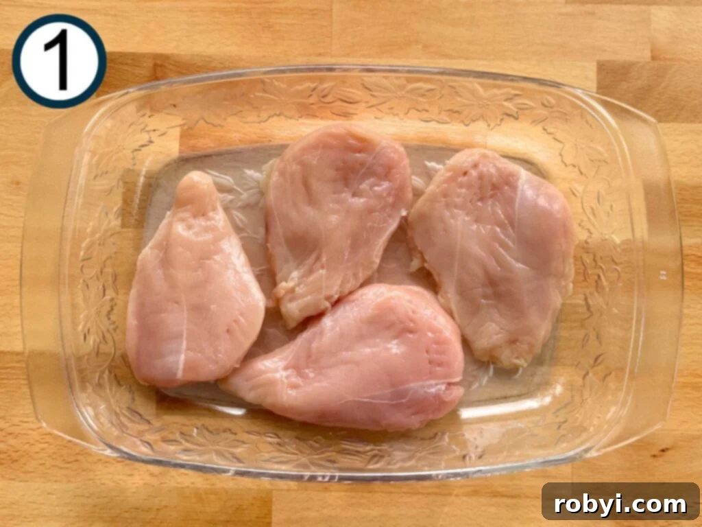 Four boneless chicken breasts in a glass dish.