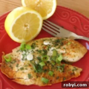 Baked lemon pepper tilapia on plate with a lemon half and fork.