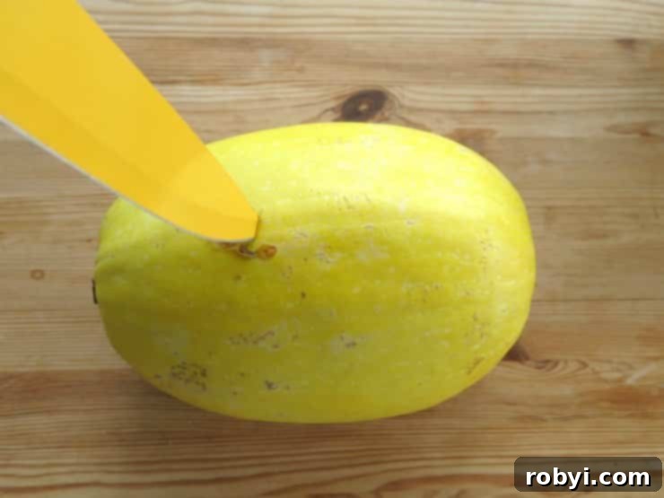 Tip of a knife inserted into the uncooked skin of a whole spaghetti squash to allow steam to escape during cooking.