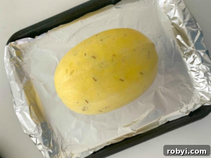 Whole spaghetti squash placed on a baking sheet lined with aluminum foil, ready for oven roasting.
