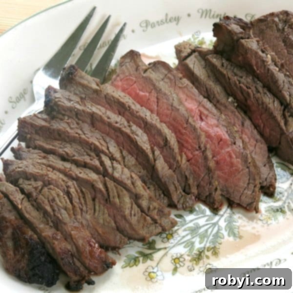 The Ultimate Oven-Baked London Broil 3 Beautifully sliced London Broil arranged on a serving platter with a fork.