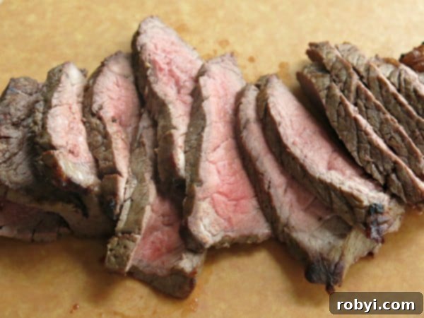 The Ultimate Oven-Baked London Broil 6 Slices of the best London Broil recipe, perfectly cut across the grain on a cutting board.