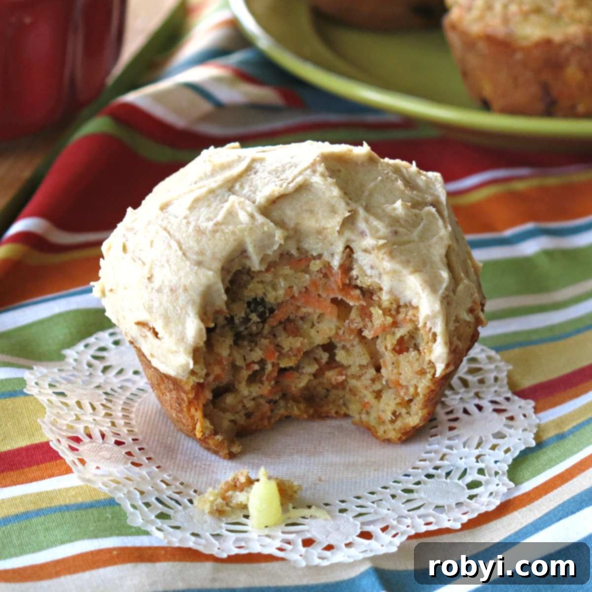 Bite taken out of healthy pineapple carrot cake muffin with cream cheese frosting.