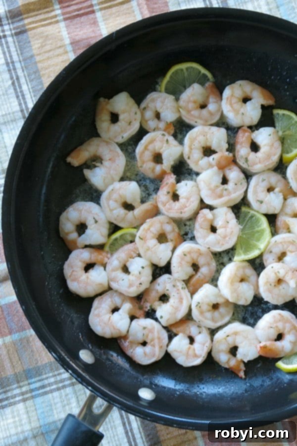Perfectly cooked skillet shrimp with fresh lemon slices in a hot pan, ready to serve.