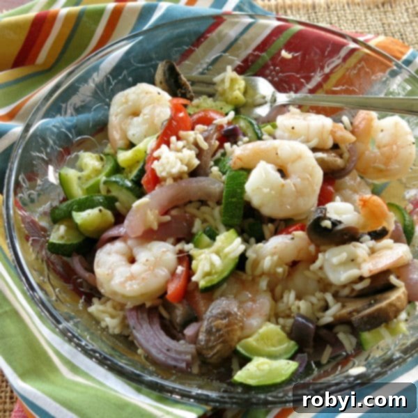 A plate featuring skillet shrimp, fluffy white rice, and a medley of colorful stir-fried vegetables.