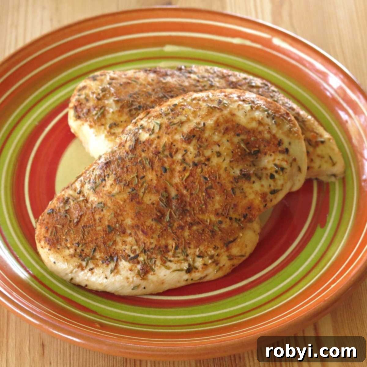 Spicy Oven-Roasted Chicken Breasts 2 Two perfectly baked blackened chicken breasts, sliced to reveal their juicy interior, served on a clean white plate with a sprig of fresh parsley.