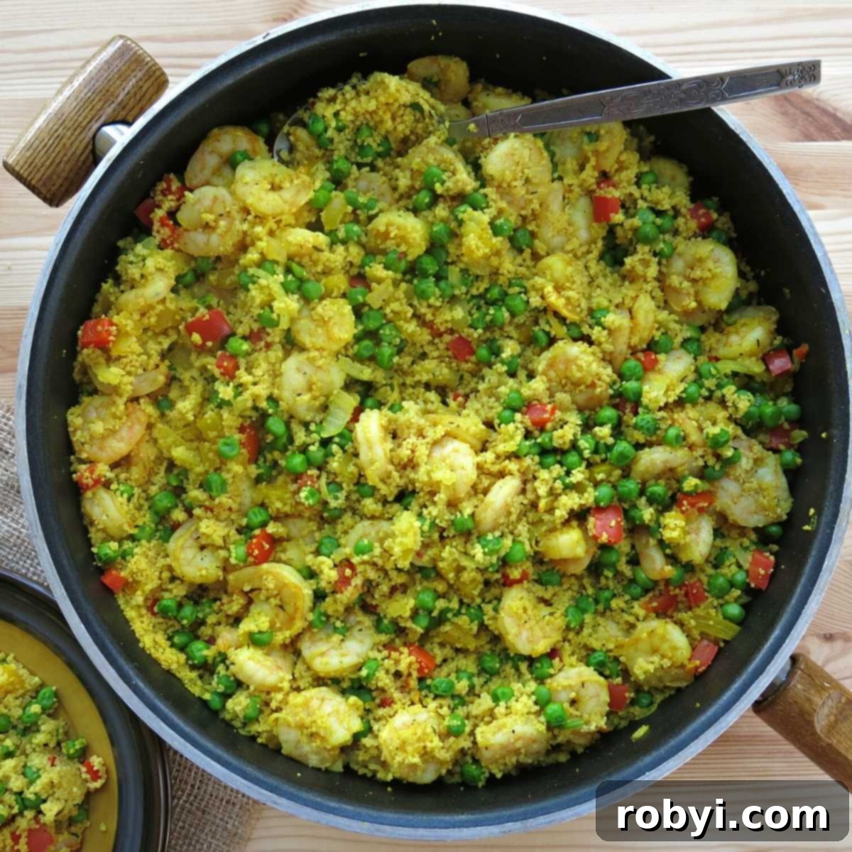 Shrimp and Couscous sizzling in a large, deep skillet, ready to be covered and finished to perfection.