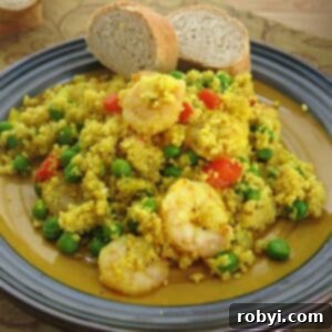 Shrimp couscous paella with peas and peppers on a plate, ready to be enjoyed.