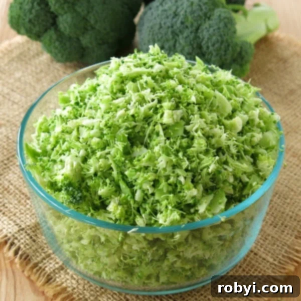 Bowl of riced broccoli with heads of broccoli behind it.