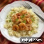 Cheesy cauliflower grits and blackened shrimp on a plate with a fork.