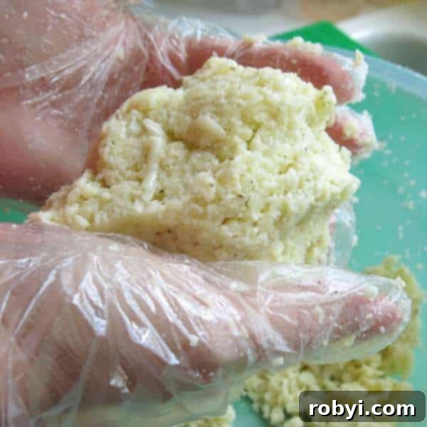 Hands pressing a ball of cauliflower pizza dough to remove excess moisture.
