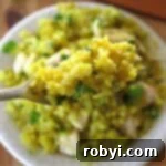 Curry cauliflower rice on a fork with more in a bowl below it.